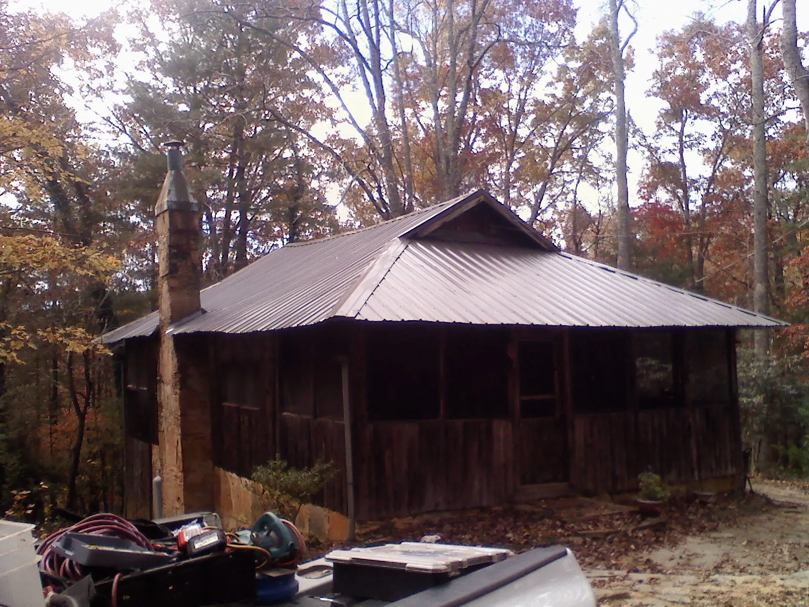 Brown metal hip roof on an old cabin with a stone chimney in Wilbur