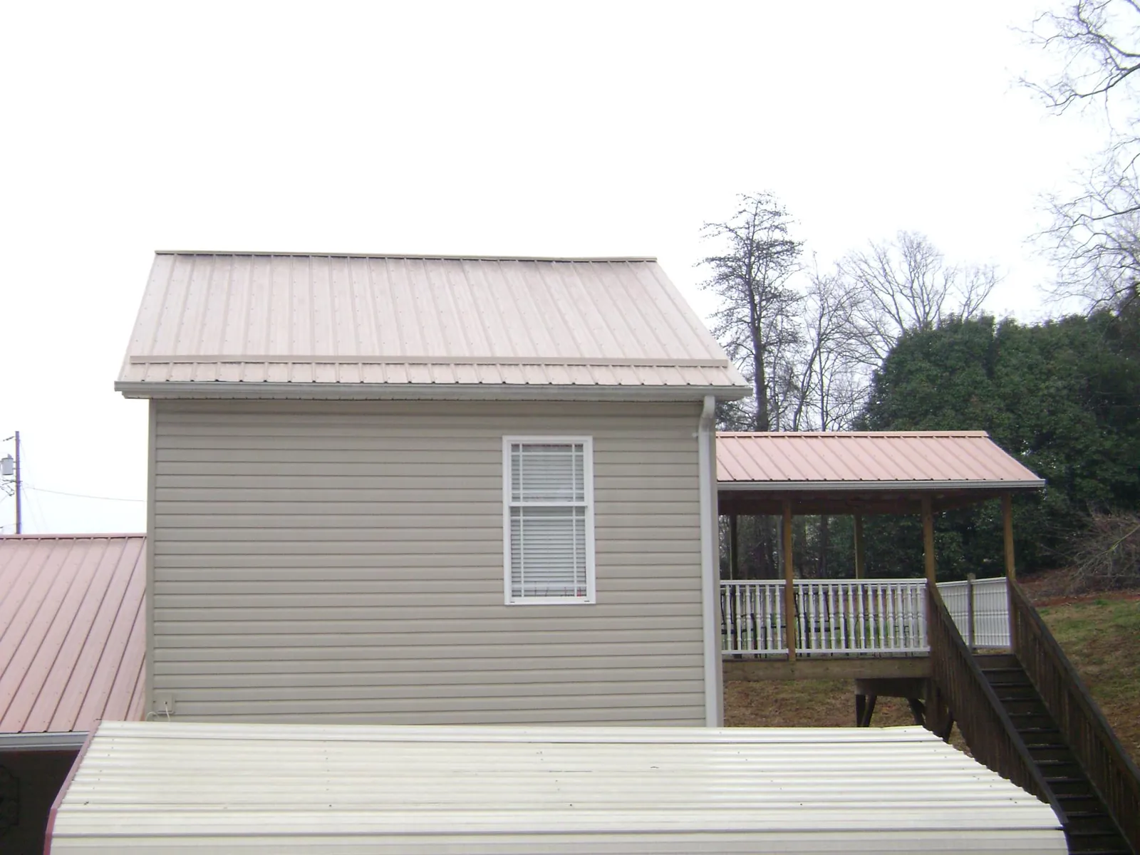 Tan metal roofs on a two story addition and attached porch, from a Roof Replacement job in Wilbur